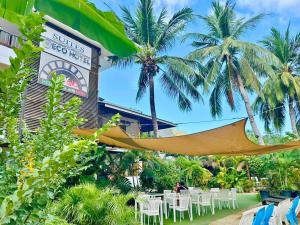 a hammock in front of a restaurant with chairs and palm trees at Suites by Eco Hotels in El Nido