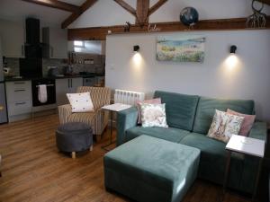 a living room with a green couch and a kitchen at Shay Bank Cottage in Keighley