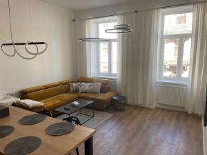 Una sala de estar con un sofá, mesas y ventanas. en Residence Drobného apartmán Park, en Brno