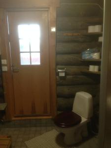 a bathroom with a toilet with a wooden wall at Ranta Äärelä in Vuotso