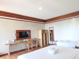 a room with a bed and a desk and a tv at Spring Hill Hotel Ruteng in Ruteng