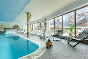 a swimming pool with lounge chairs and a table and a pool at Apartments Sunseit'n in Sesto