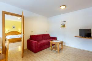 a living room with a red couch and a television at Apartments Sunseit'n in Sesto +12 photos
