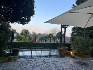 a fence with an umbrella next to a pool at Villa Santa Chiara Lesa - appartamento vista lago con piscina in Lesa