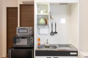 Una pequeña cocina con fregadero y microondas. en Ocean 西九条, en Osaka