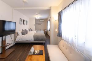 Un dormitorio con una cama, un sofá y un televisor. en Ocean 西九条, en Osaka