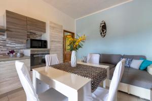 a dining room and living room with a table and chairs at Villetta I Pitosfori in Palmadula +7 photos