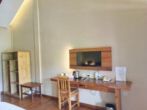 a room with a desk with a television on a wall at Spring Hill Hotel Ruteng in Ruteng