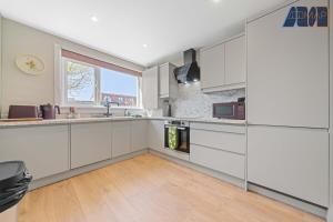 a kitchen with white cabinets and a wooden floor at 2 Bed Sleeps 4 in Dunfermline in Cairneyhill
