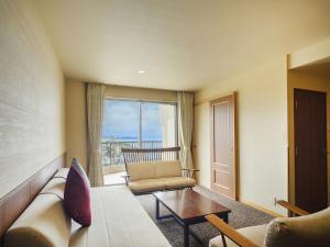 a living room with a couch and a table and a window at KAMENOI HOTEL Atami in Atami