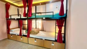 um quarto com 3 beliches e cortinas vermelhas em The Backpackstack Hostels and Cafe em Ujjain