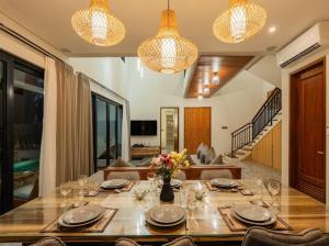 une salle à manger avec une table, des verres et des fleurs dans l'établissement Villa Sanur river view, à anur