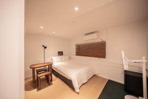 a bedroom with a bed and a table and a window at Stay A Hotel Gwangan in Busan