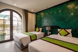 河内Charmpearl Hotel & Suites的一间有绿墙的房间里有两张床