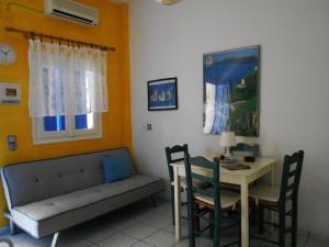 a living room with a table and a couch and a table and chairs at Meltemia Studio Samos with pool in Kámpos