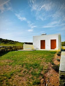 un edificio blanco con puertas rojas en un campo en Gaia House, en Kampos