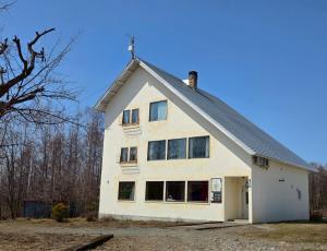 a white house with a gambrel roof at Auberge Ninguruforet in Biei