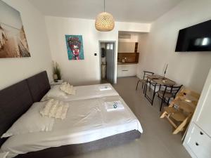 a bedroom with a large white bed and a table at Studio apartman Velvet in Biograd na Moru