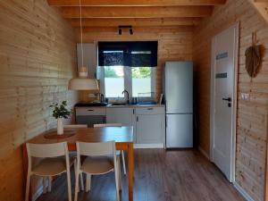 a kitchen with a table and chairs and a refrigerator at Domki Północ-Południe in Karwia