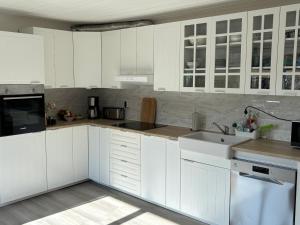 a white kitchen with white cabinets and a sink at Familjehus Villa Kunterbunt in Alstermo