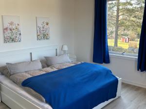 a bedroom with a bed with a blue blanket on it at Familjehus Villa Kunterbunt in Alstermo