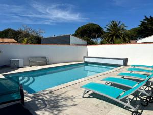 a swimming pool with lounge chairs next to a wall at ღ Villa des Grasses - Piscine Chauffée, Jardin & Wifi in Le Bois-Plage-en-Ré