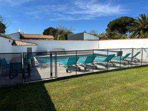 a fence with chairs next to a swimming pool at ღ Villa des Grasses - Piscine Chauffée, Jardin & Wifi in Le Bois-Plage-en-Ré
