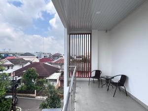 a balcony with two chairs and a table on it at AJ Kost Homestay in Palembang