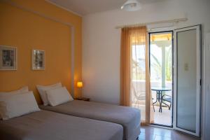 a bedroom with a bed and a balcony with a table at Stefanie Studios in Egina