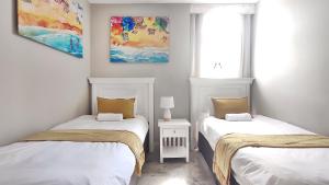 2 Einzelbetten in einem Zimmer mit 2 Fenstern in der Unterkunft La Ballito 107 in Ballito
