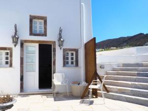 Un patio con dos sillas y una puerta y escaleras. en The Palm Rock, Finikia Santorini, en Foinikiá