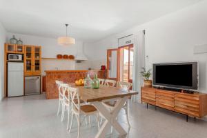 a kitchen with a table with chairs and a television at Ca N'Alicia Des Bosch in Illes Balears