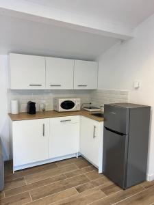une cuisine avec des armoires blanches et un réfrigérateur en acier inoxydable dans l'établissement Studio cosy indépendant et détaché dans une villa avec parking gratuit, à Marseille 3 autres photos