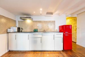 La cuisine est équipée de placards blancs et d'un réfrigérateur rouge. dans l'établissement Au Coeur de l'Ecusson - Appartement de caractère, à Montpellier 4 autres photos