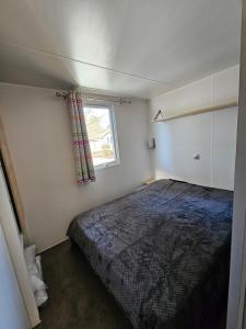 a small bedroom with a bed and a window at mobil home in Villeneuve-lès-Maguelonne