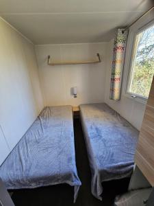 two beds in a small room with a window at mobil home in Villeneuve-lès-Maguelonne