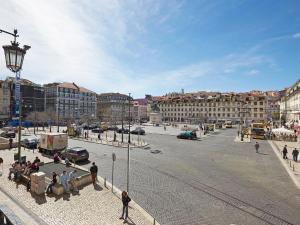 eine Gruppe von Menschen, die auf Bänken auf einer Stadtstraße sitzen in der Unterkunft Sonel Investe Figueira Boutique Apartment by Get Your Stay in Lissabon