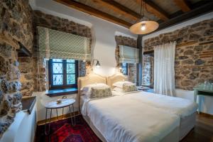 a bedroom with a large white bed and a stone wall at Robolo Boutique Hotel by H&T in Litochoro