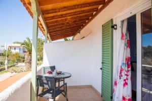 a small table on the porch of a house with a green door at Stefanie Studios in Egina