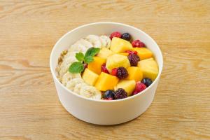a bowl of cereal with fruit in it on a table at BEB5 Okinawa Seragaki by Hoshino Resorts in Onna