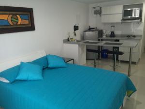a bedroom with a blue bed and a kitchen at Rent Apartments Manizales in Manizales