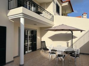 ein Tisch und Stühle mit einem Sonnenschirm auf einer Terrasse in der Unterkunft Maribel's Place in Funchal + 13 Fotos