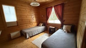 ein Schlafzimmer mit zwei Betten in einer Blockhütte in der Unterkunft Cozy Cottage in Kerimaa in Savonlinna
