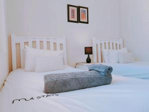 two beds in a room with white sheets and pillows at The Waves Empire Apartment in Muizenberg