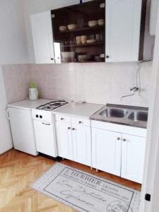 a kitchen with white cabinets and a sink and a rug at EmTo Suhi Potok in Jesenice