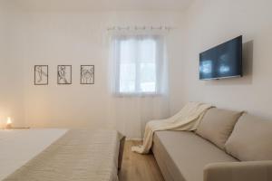 a white living room with a couch and a window at Villa Maison Rosabianca Country Escape - Costa Smeralda in Cugnana Verde