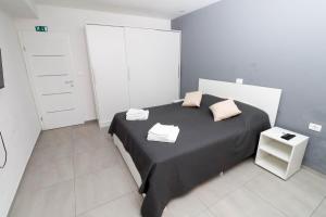 a bedroom with a bed with black sheets and pink pillows at AMB Apartmaji in Spodnje Škofije
