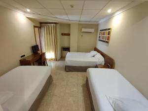 a hotel room with two beds and a desk at Hostal Moreno in Silla
