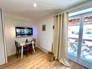 a dining room with a table and a tv on a wall at La Poulie - Apartment with Balcony and Free Privative Parking - Close to Colmar in Sainte-Croix-en-Plaine