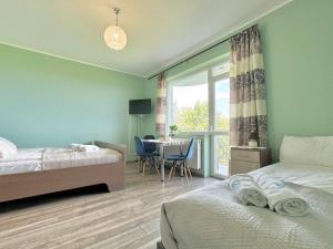 a bedroom with two beds and a table and a window at Błękitna Przystań - pokoje z widokiem na Zatokę in Swarzewo